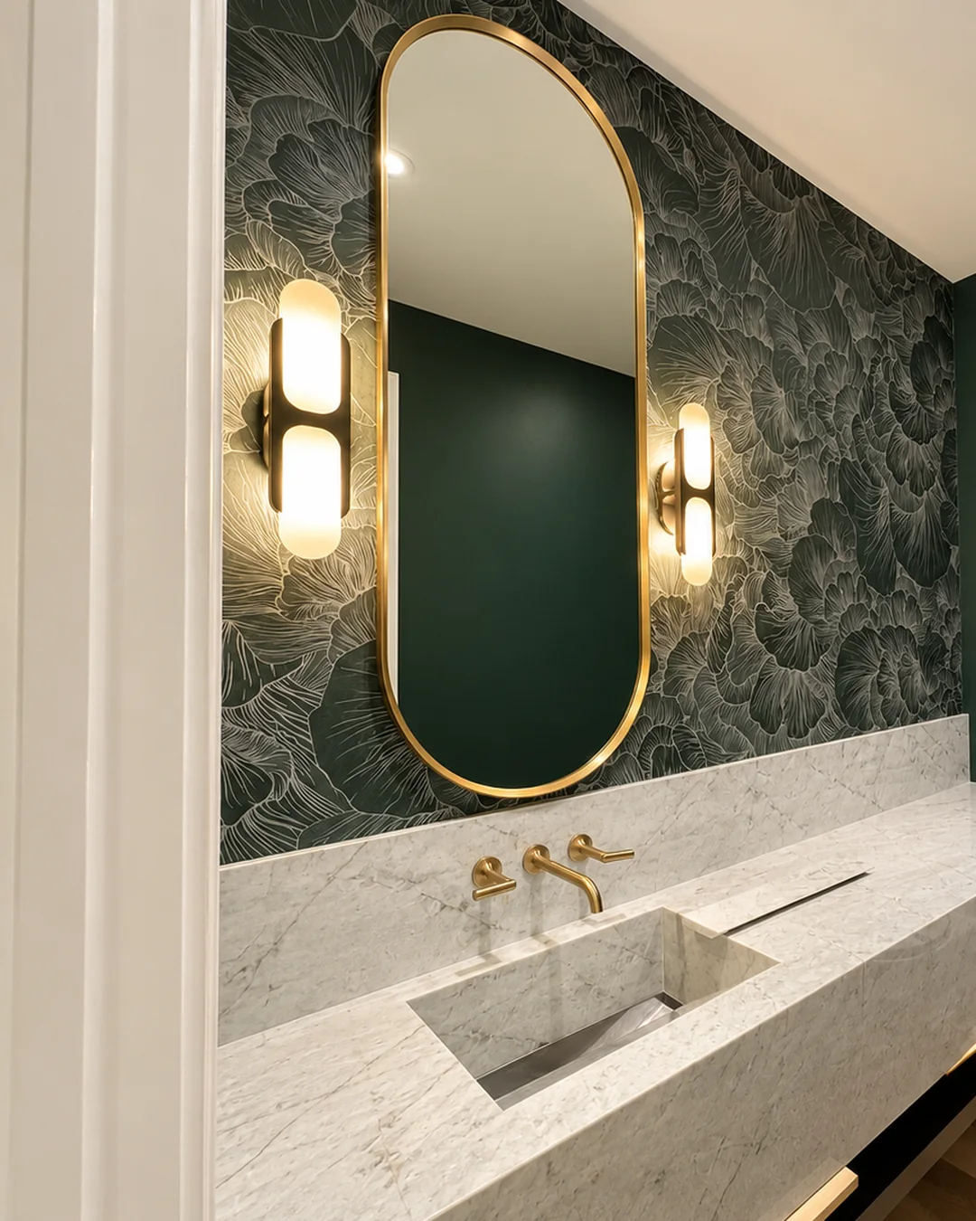 Green powder room with botanical wallpaper, an oval brass mirror and a marble sink