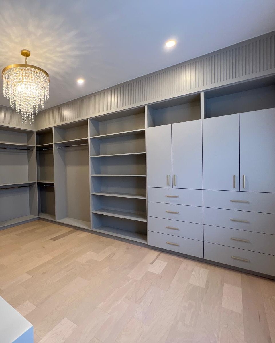 Walk-in closet with grey painted built-in cabinets and fluted trim