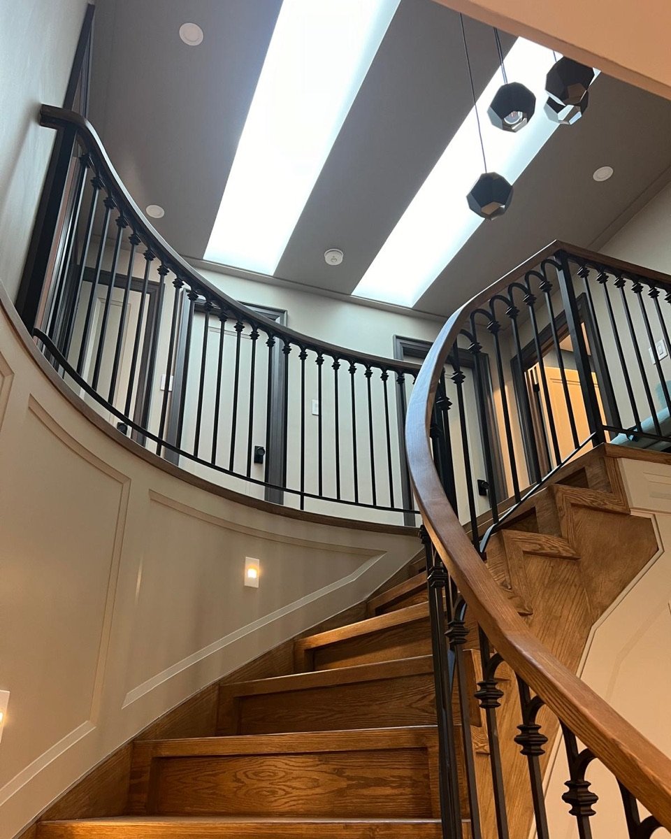 Curved staircase with stained oak treads and handrail under skylights