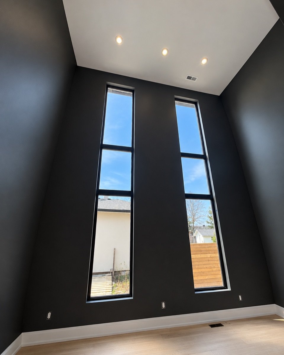 Black painted walls in a double-height room with tall windows