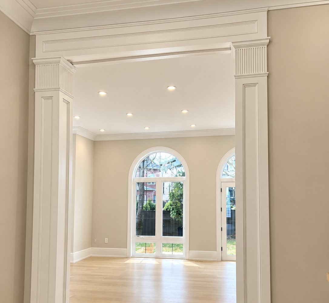 Freshly painted living room with white columns, crown moulding and arched windows