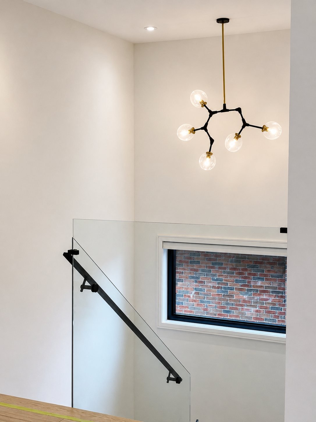 Painted stairwell with a modern chandelier and a glass railing