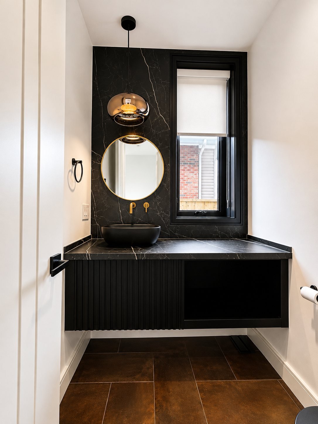 Powder room with a black stone feature wall, round mirror and freshly painted walls