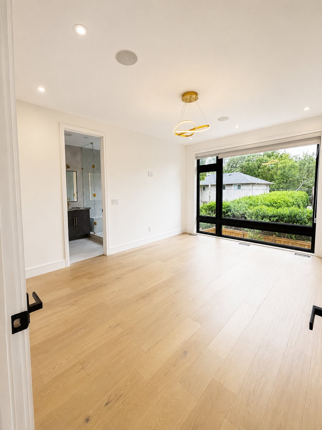 Primary bedroom with freshly painted walls, a sculptural pendant and a large window