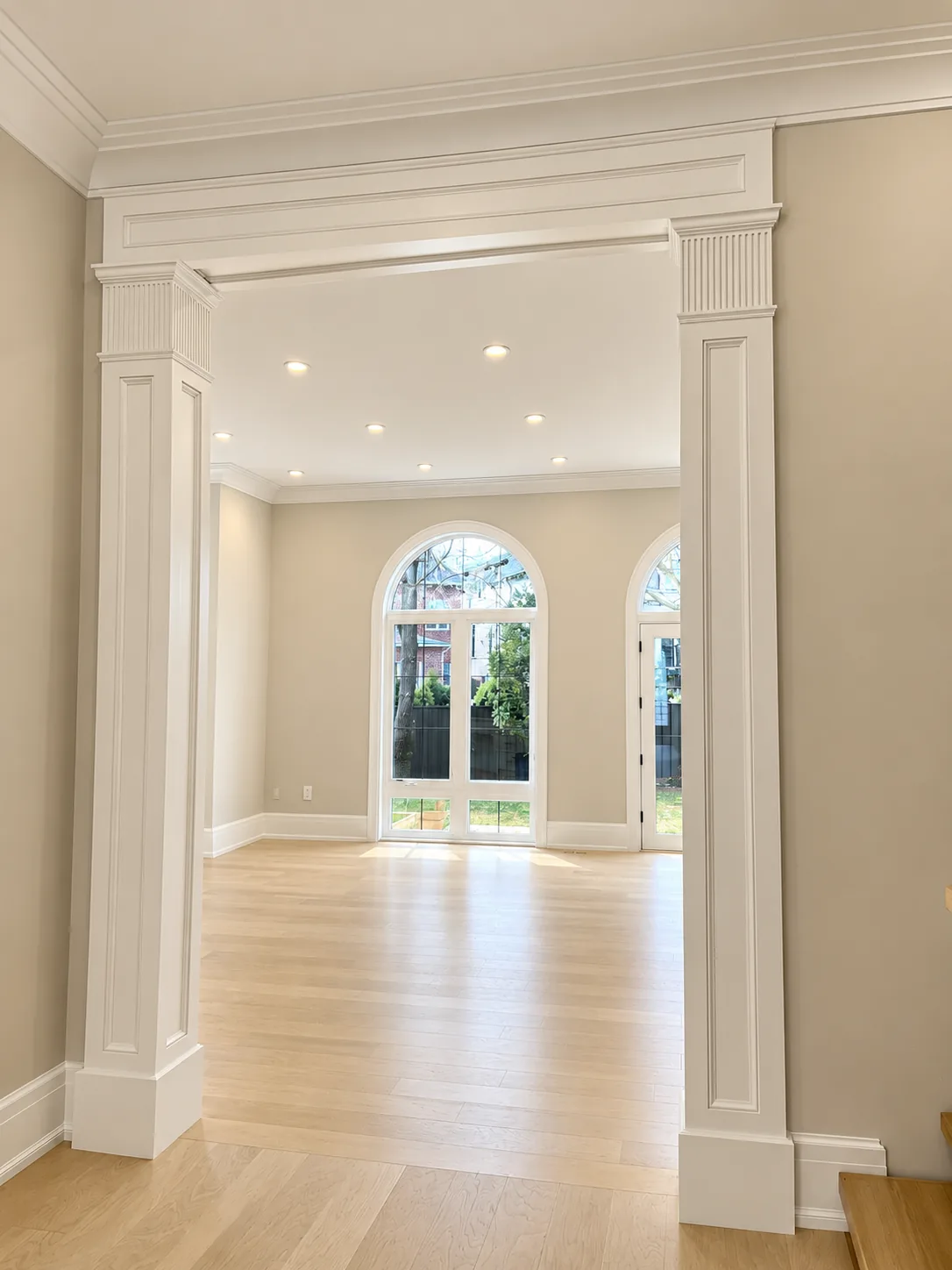 Painted cased opening with white columns leading to a room with arched windows