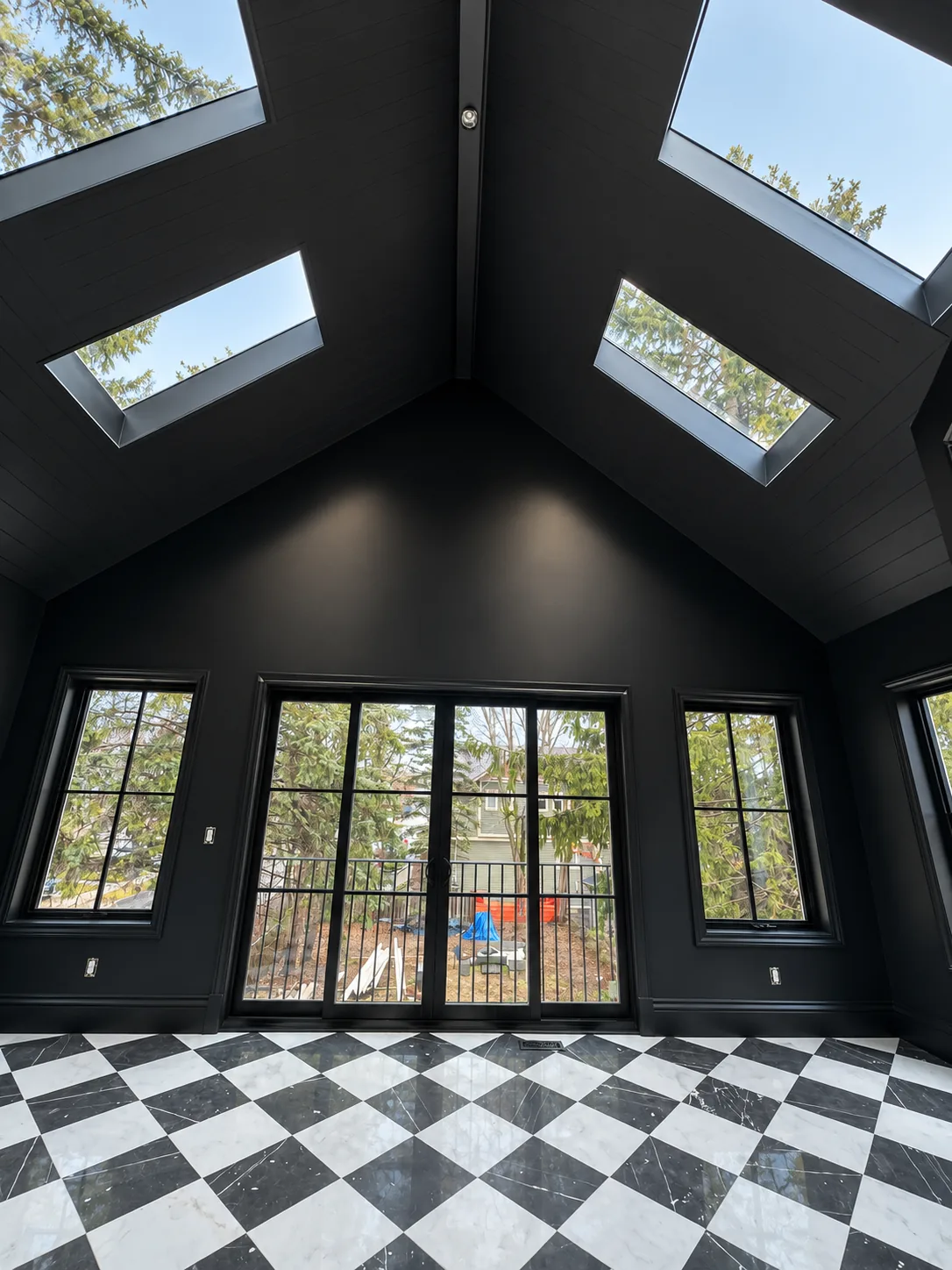 Vaulted room with black painted walls and ceiling, skylights and a checkered floor