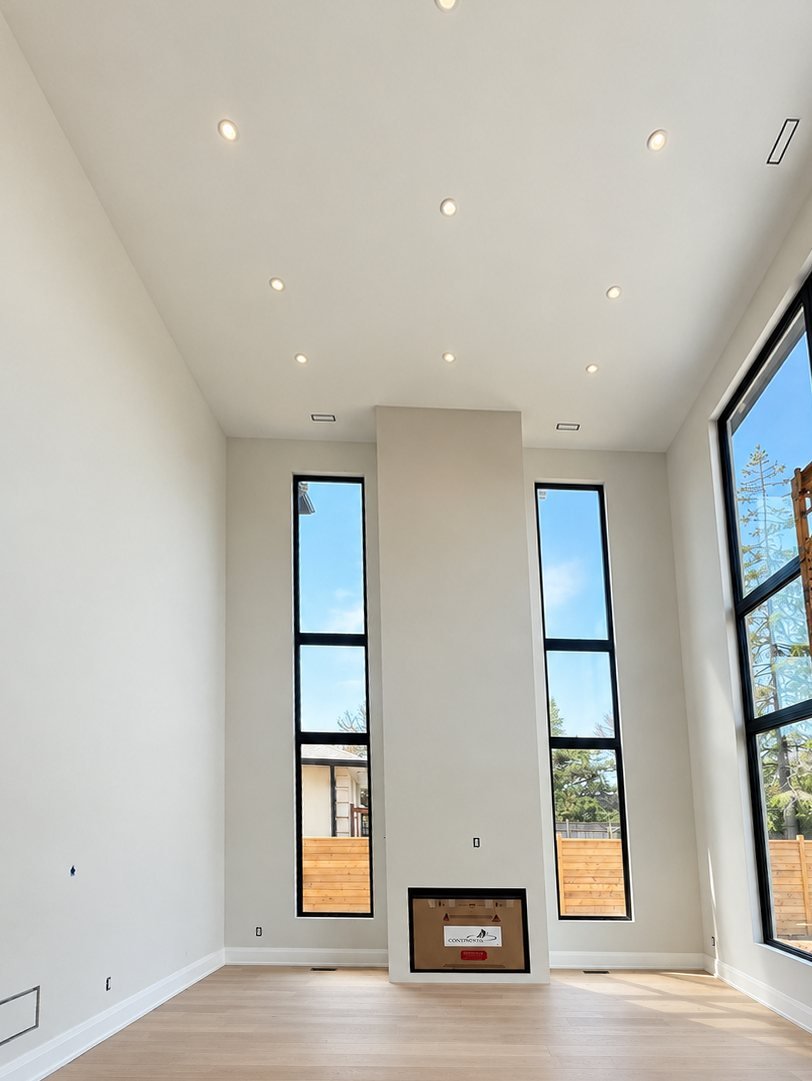 Double-height living room with freshly painted walls and tall windows
