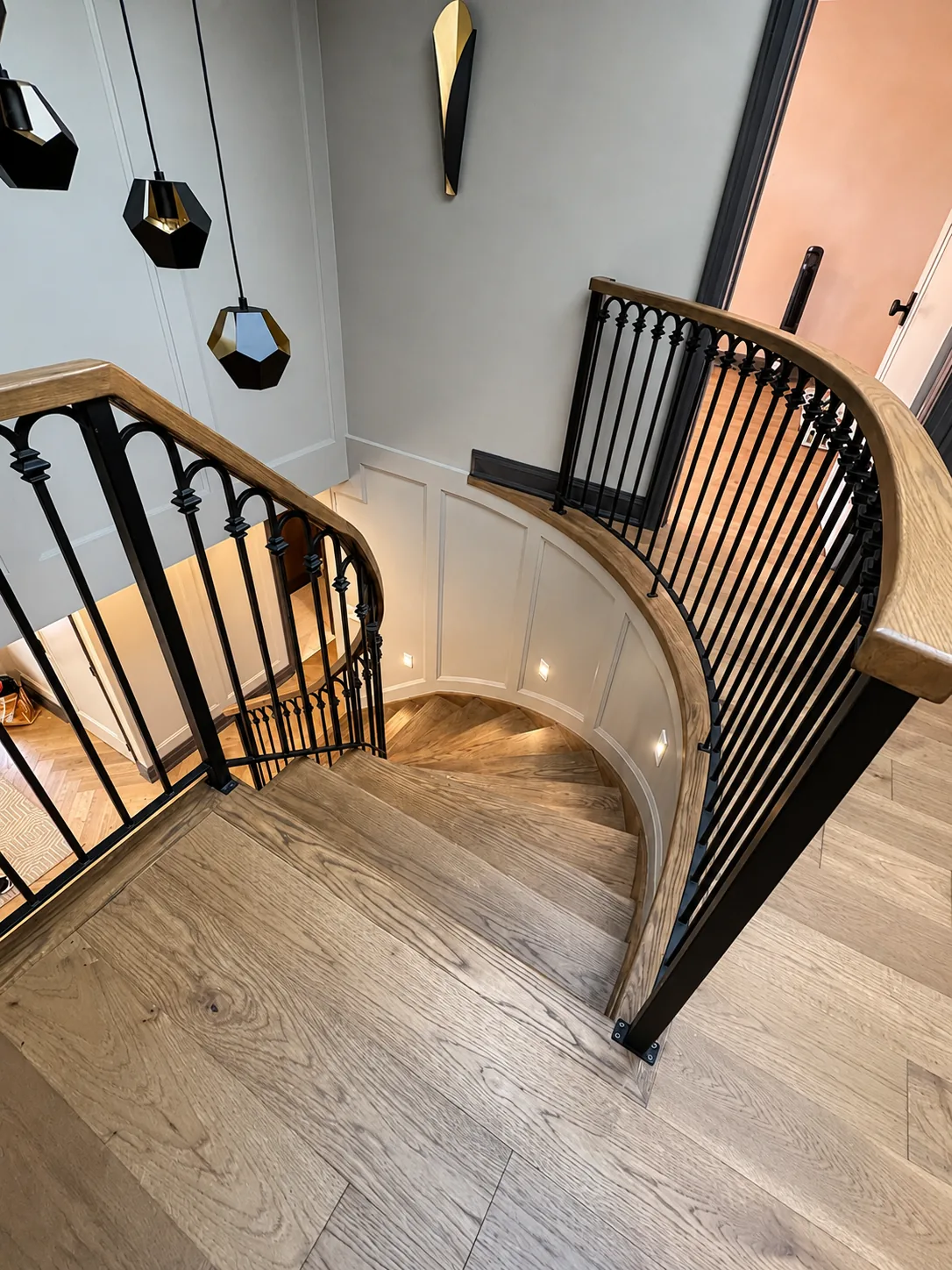 Curved staircase with a stained oak handrail and black balusters, seen from above
