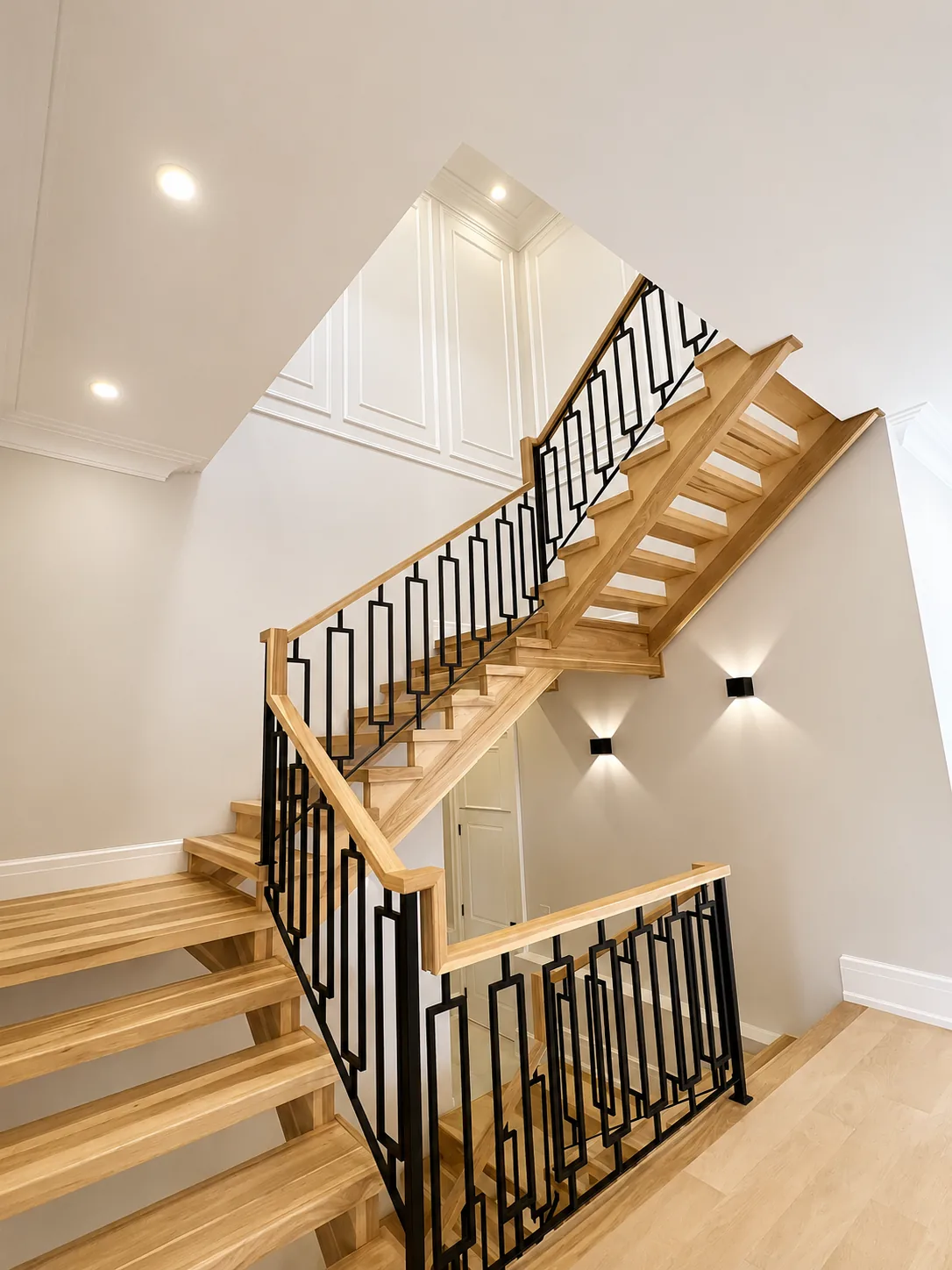Oak staircase with a stained handrail and black metal balusters, seen from below