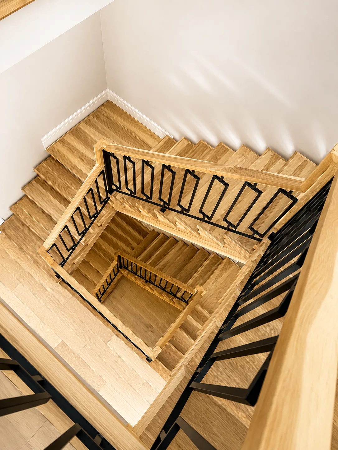 Oak stairwell with stained handrails and black balusters, seen from above
