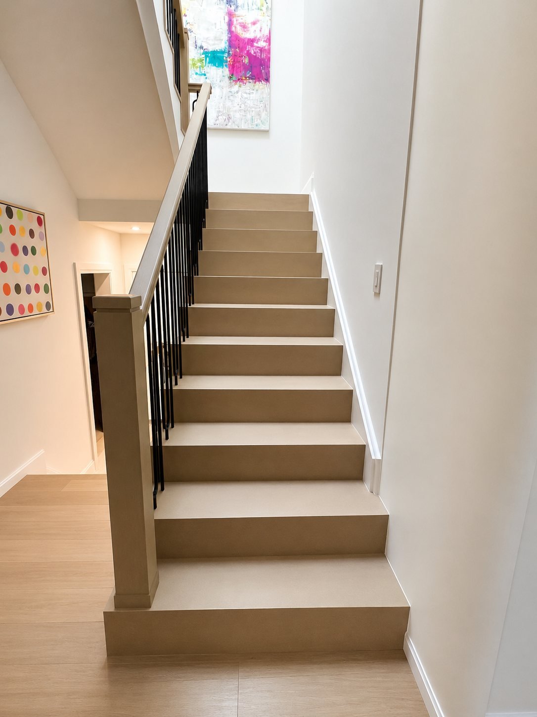 Straight staircase with finished steps and a black railing