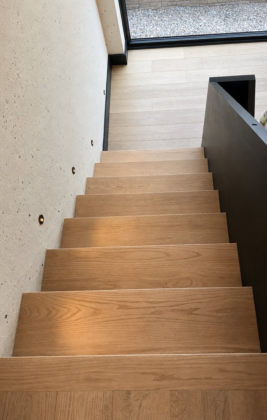 Oak stair treads and a black stringer seen from the top landing