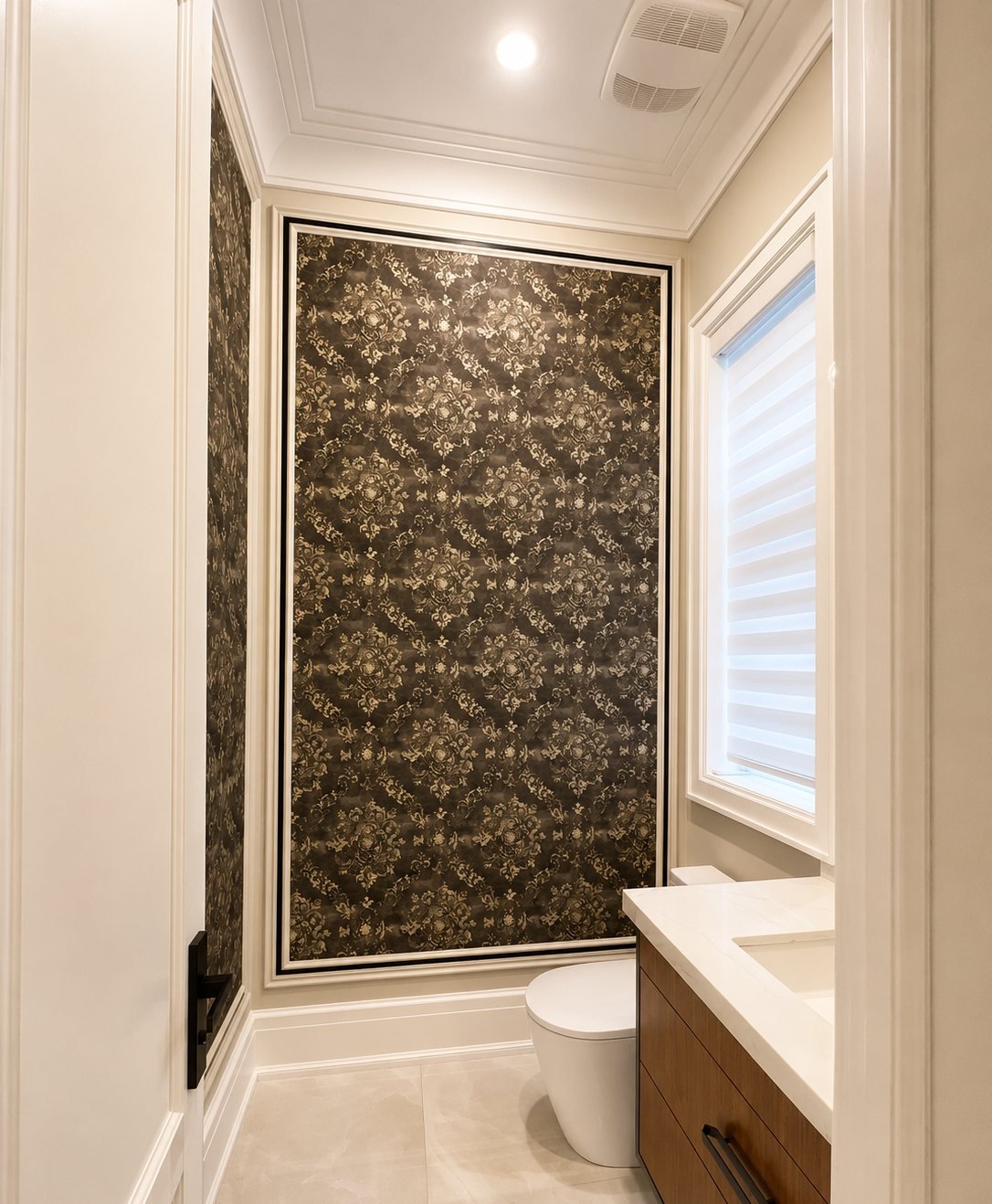 Powder room with dark ornamental wallpaper framed in white panel moulding