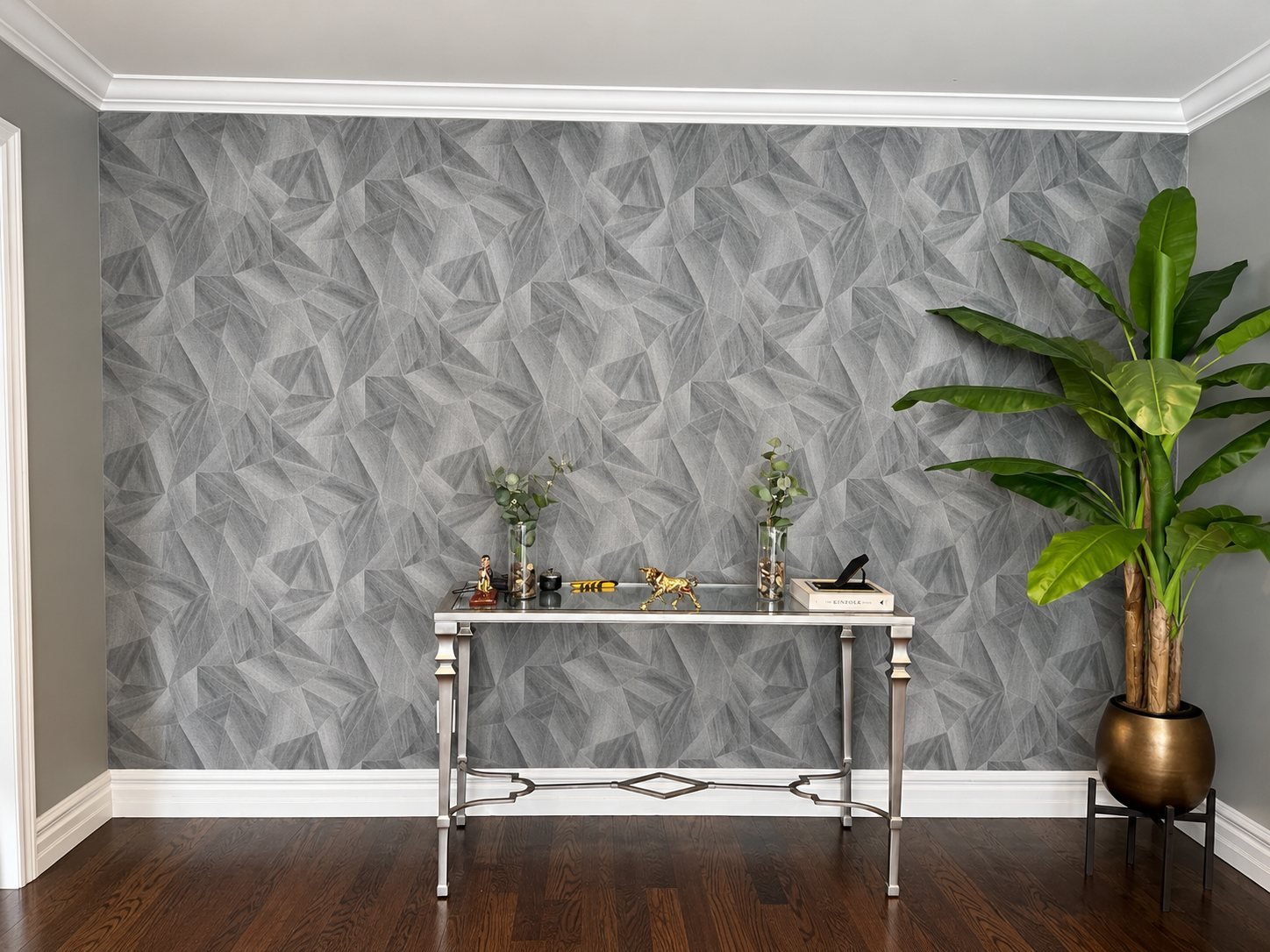 Grey geometric wallpaper accent wall with white crown moulding