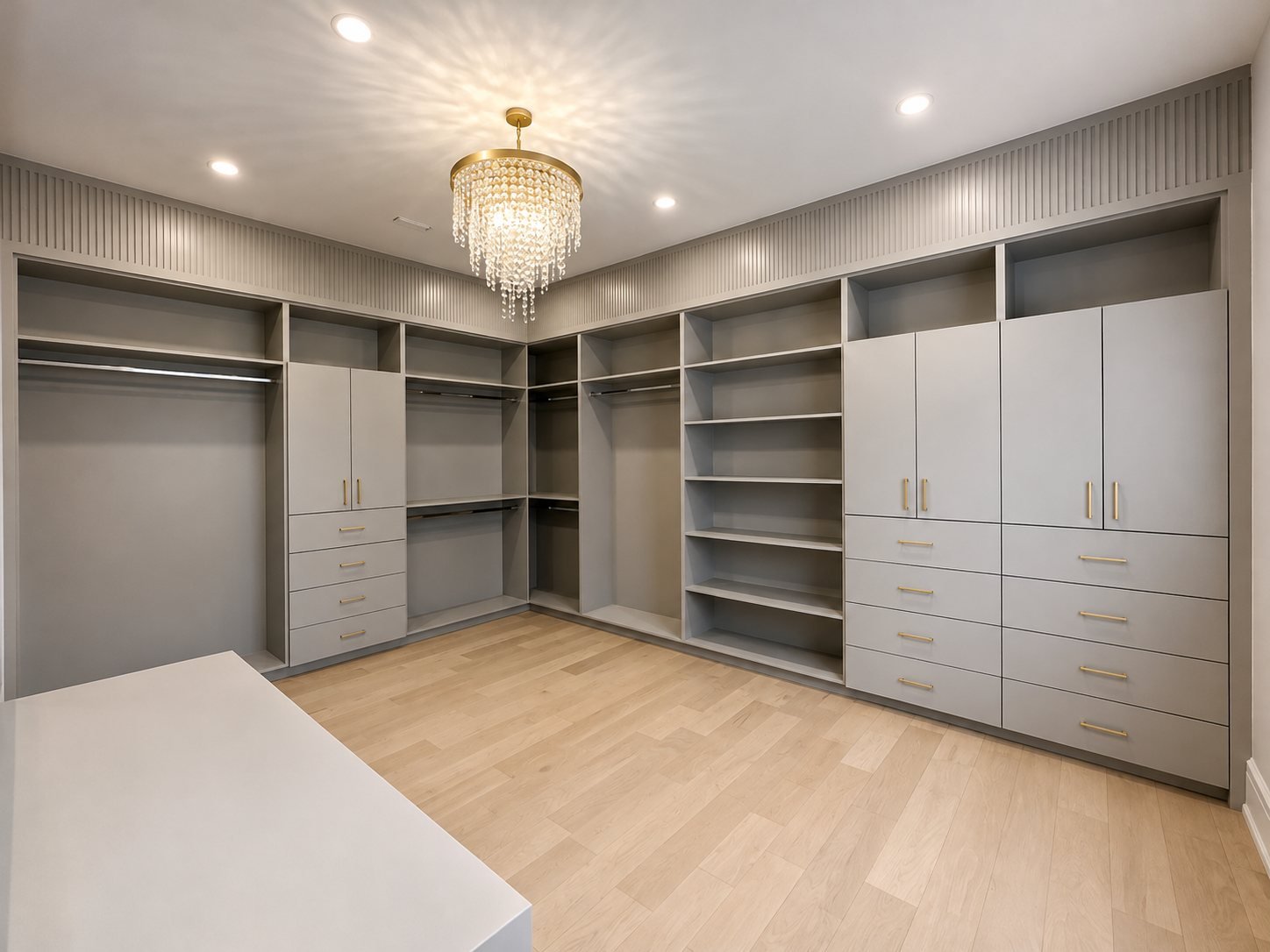 Spray-finished grey built-in cabinets and drawers in a walk-in closet with a crystal chandelier
