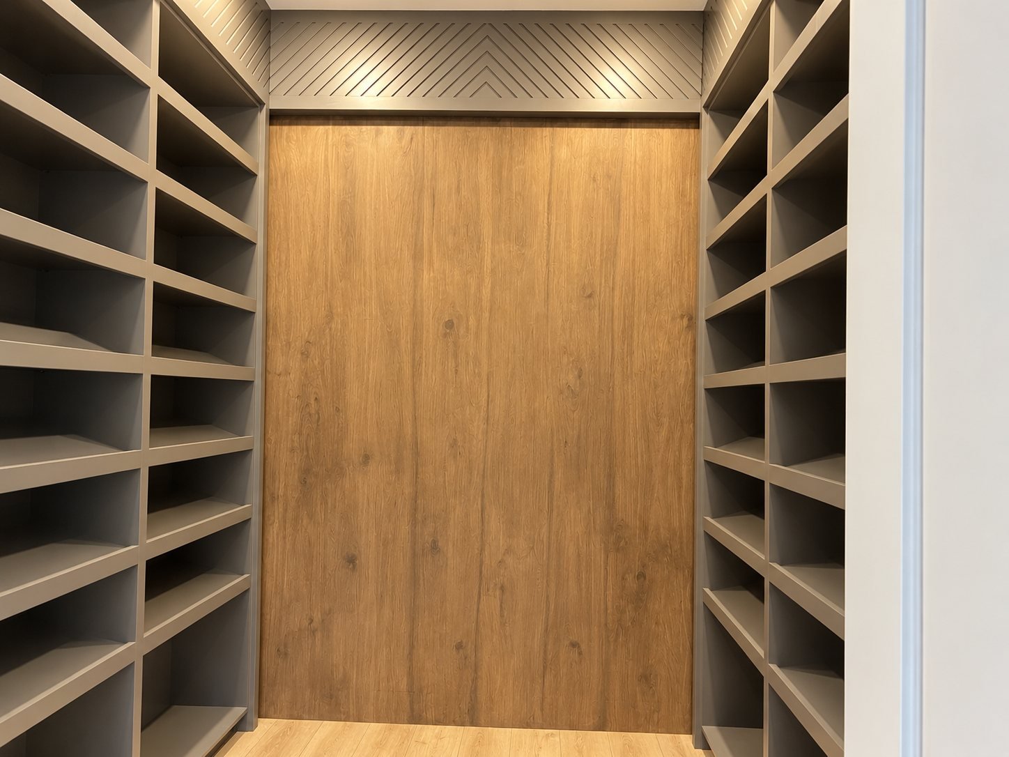 Spray-finished grey closet shelving with a wood feature panel
