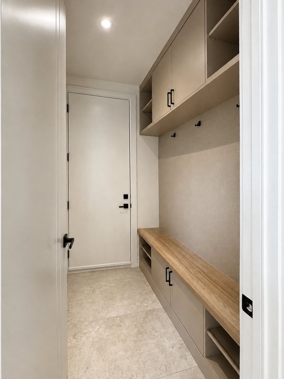Spray-finished beige mudroom cabinets with a wood bench